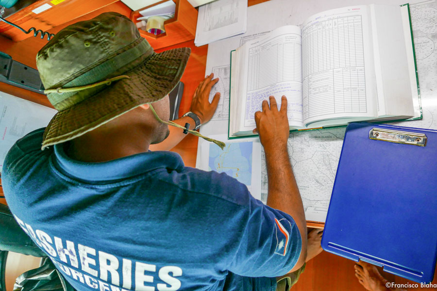 Photo from above and behind of man checking documentation on ship. Photo Francisco Blaha.