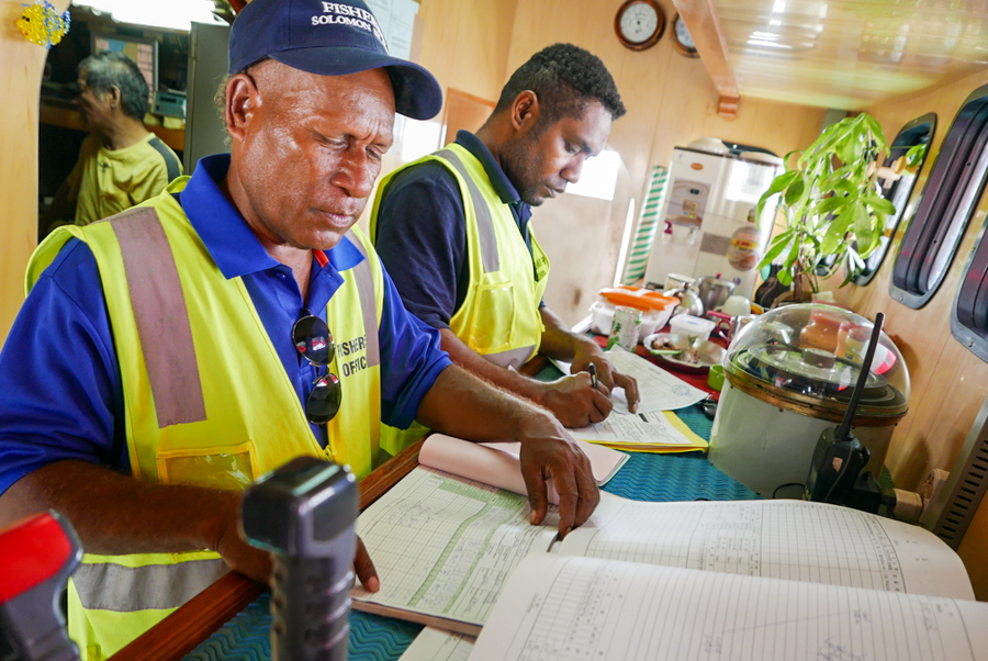 Two officers check log sheets of a Taiwanese longliner in Solomon Islands photo Francisco Blaha