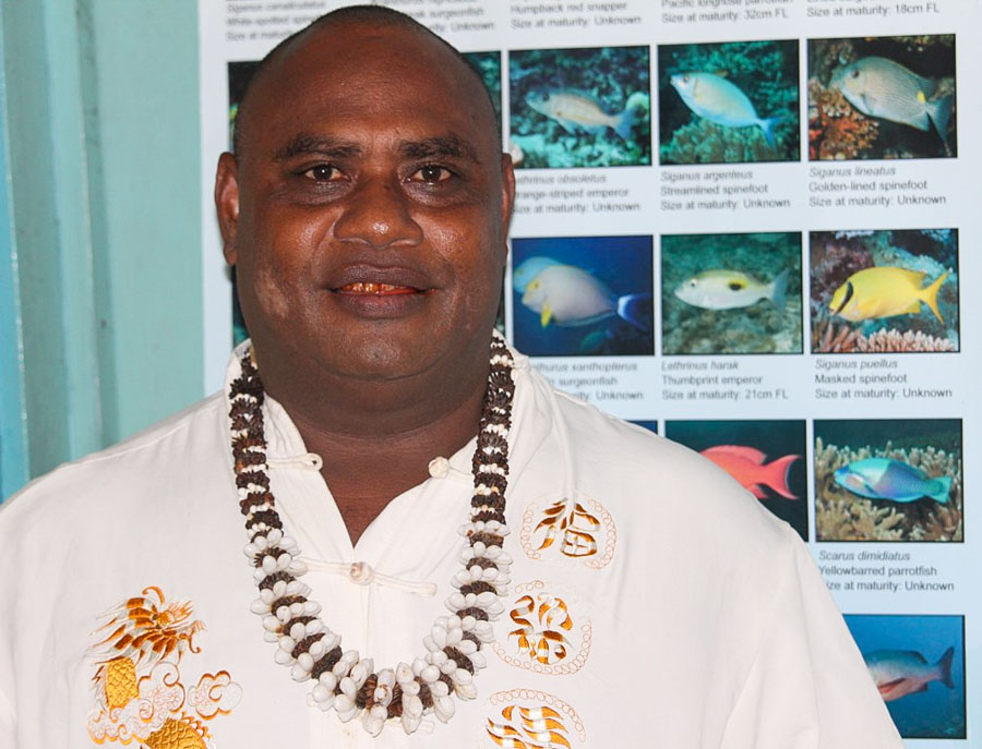 Malaita Provincial Fisheries boss Martin Jasper, head and upper body photo of man standing in front of poster of reef fishes.