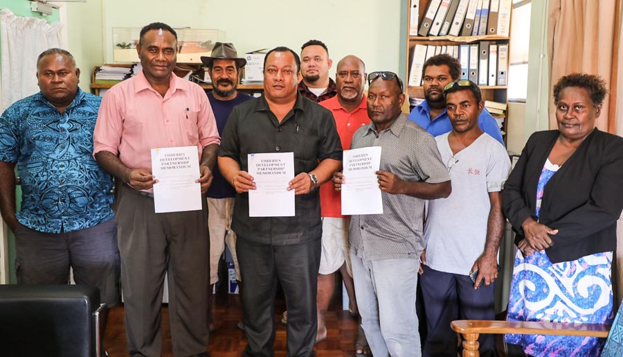 In Solomon Islands, nine men and one woman stand for photo in a room. Three of them hold in front of them copies of the same document. They are RIFF chair Lesley Assad Norris , the MP for Savo–Russells, the Hon. Dickson Mua, and Central Islands Province Premier Stanley Manetiva