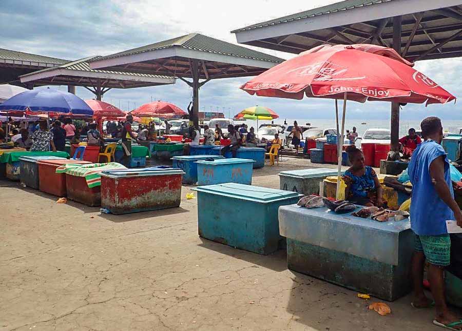 Fish vendors at Honiara. People work among ice-chests under the shade of shelters or umbrellas. Photo Sunday Isles.