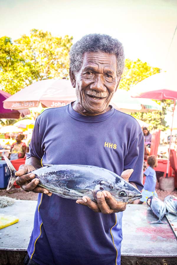 Chief of Solomon Islands village Vaivila, Robert Satu, is a longtime settler, fisher and fish vendor at the village. He stands at fish market with fish for sale in his hands. Photo: George Maelagi.