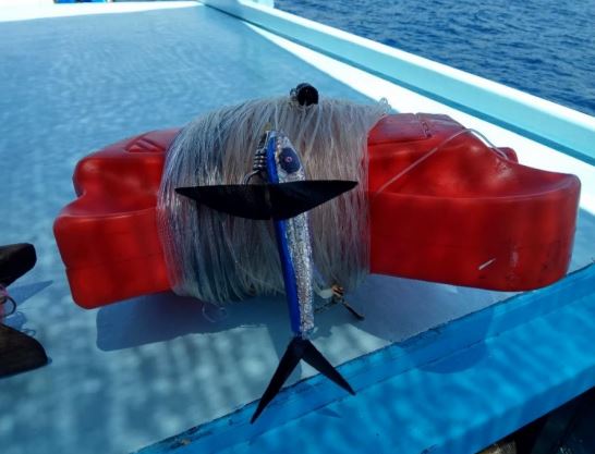 A lure attached to a hand line, rolled up on the deck of a boat