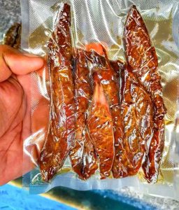 part of a hand holding a small packet of vacuum-packed smoked fish
